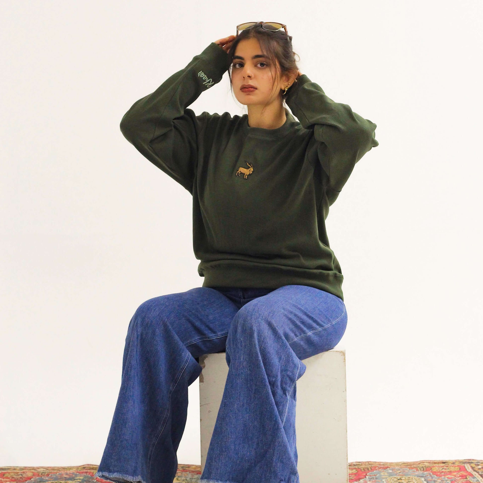 Khaar Markhor Knit Sweater in Forest Green - Female model sitting